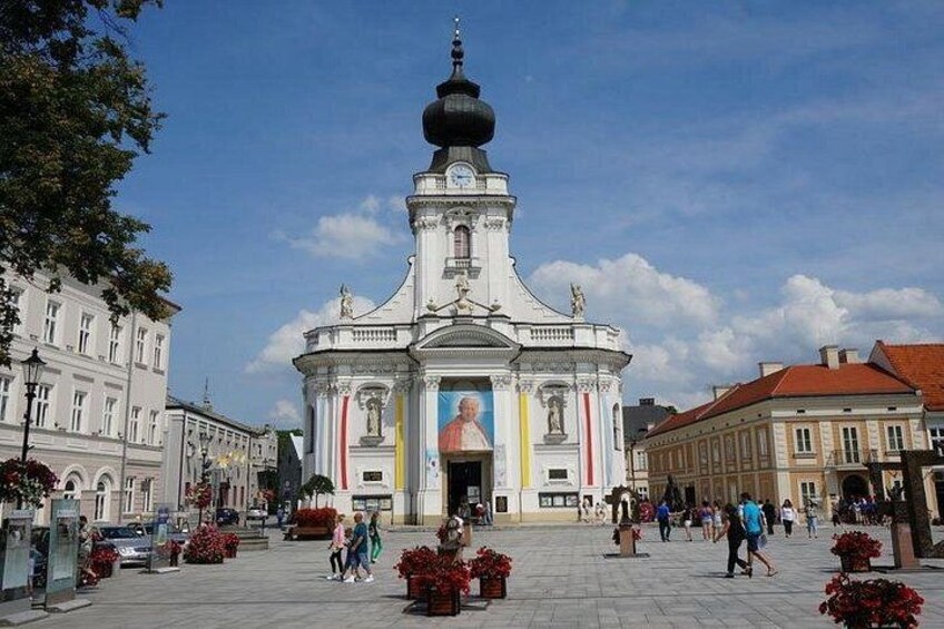 A historic building with a dome, surrounded by pedestrians and red flowers. 3