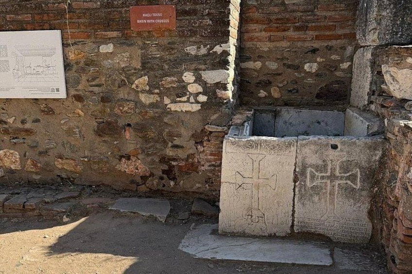 A stone wall with a cross-shaped marking, a sign with text, and a brick structure. 4