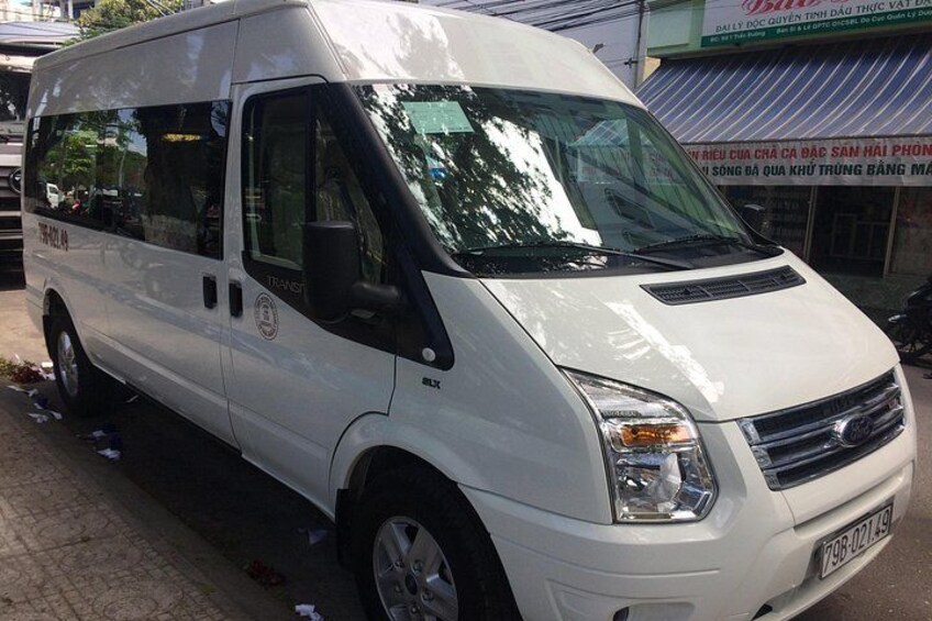 A white van parked on a street with a storefront in the background. 2