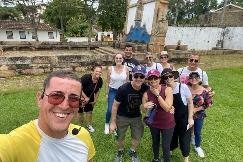 A group of people posing in a grassy area with historical structures in the background. 1