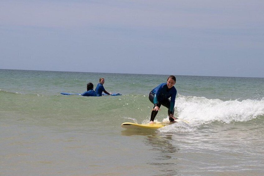 A person surfing on a yellow board, with calm ocean water and another person in the background. 3