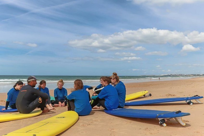A group of people sitting on the beach with surfboards. 3