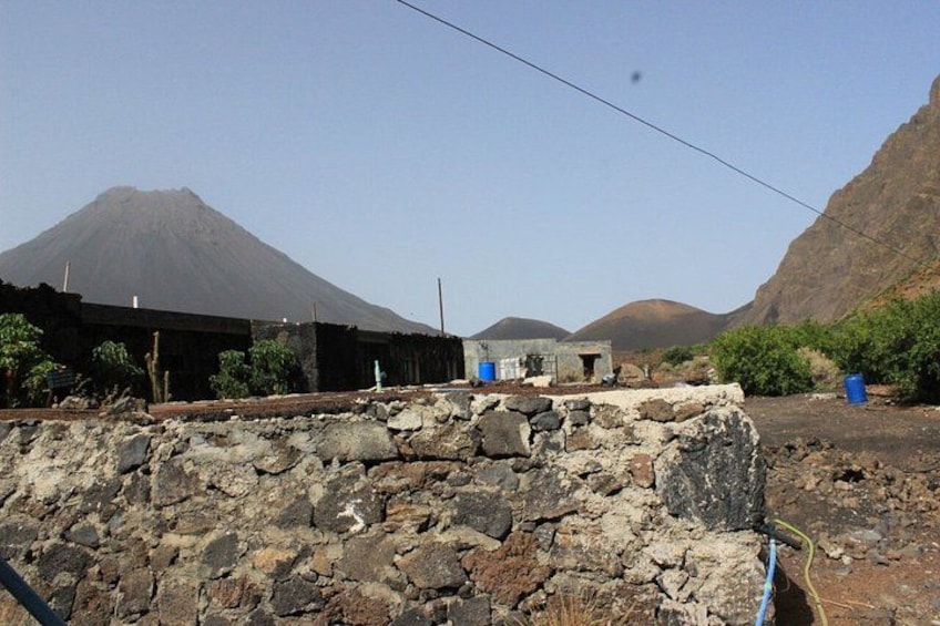A stone wall, a building, and a mountain in the background. 5