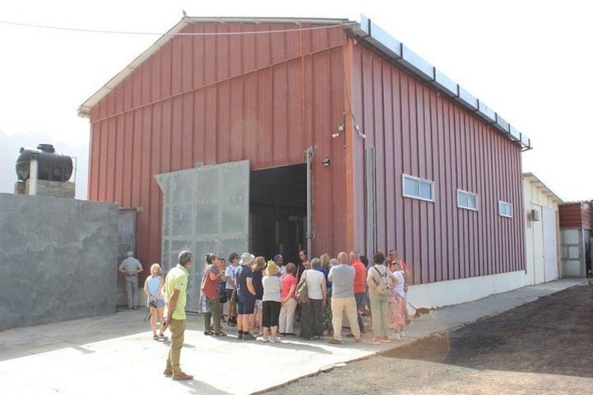 A group of people standing outside a red building with a large open door. 2