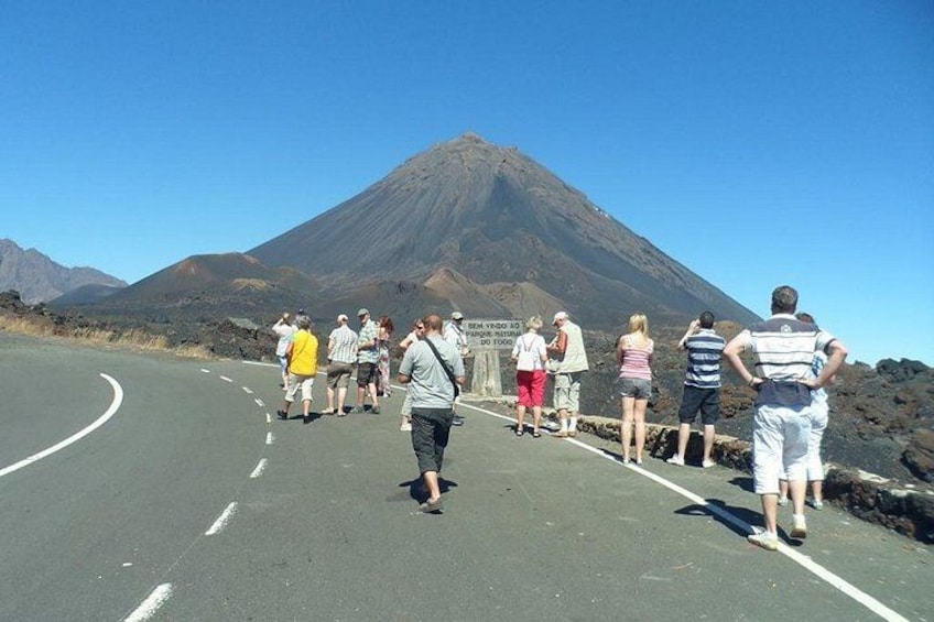 Un grupo de personas de pie en una carretera con una montaña al fondo. 2