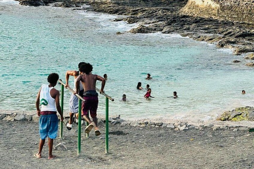 Children playing near a rocky shoreline with clear water. 2