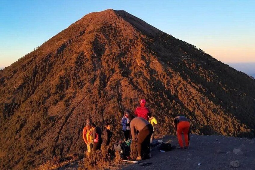 A group of people hiking on a mountain with a volcano in the background. 2