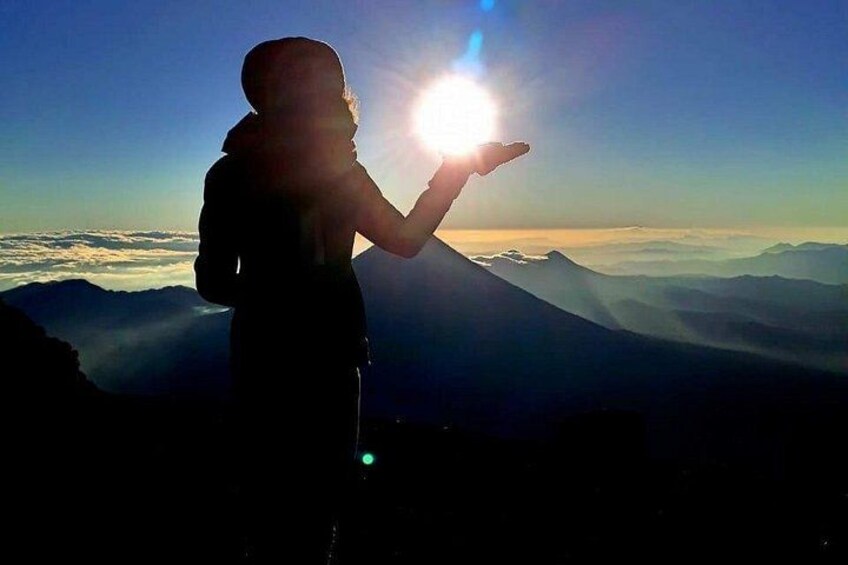 A person standing on a mountain with the sun shining behind them. 5