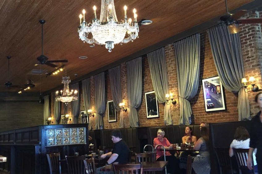 A restaurant interior with brick walls, chandeliers, and framed pictures. 5