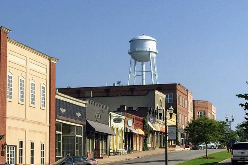 A street with buildings, a water tower, and cars. 3
