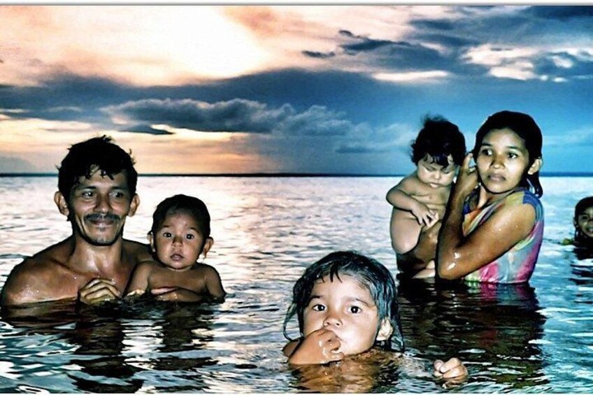 A family of five in a body of water with a sunset in the background. 1