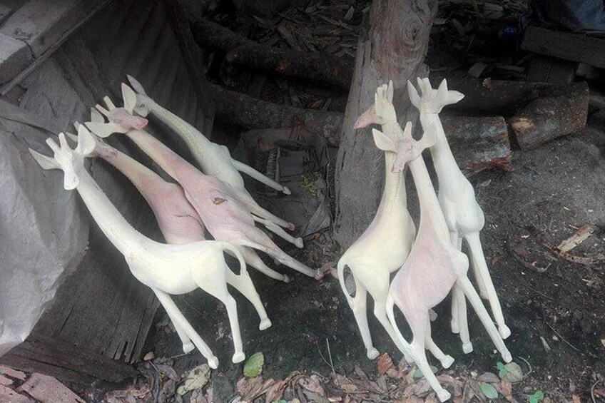 Un grupo de esculturas de ciervos blancos al aire libre, algunos apoyados en un árbol. 4