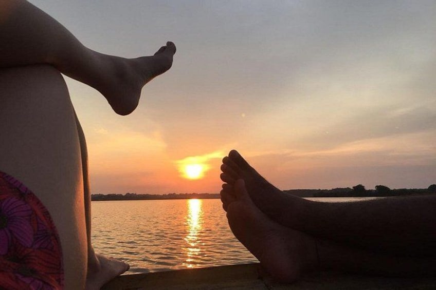 A sunset over a body of water with a person's feet on a dock. 1