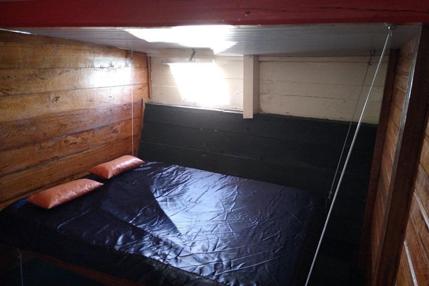 A wooden bunk bed with a black mattress and orange pillows. 4