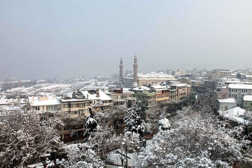 A snowy cityscape with buildings, a mosque, and a minaret. 1
