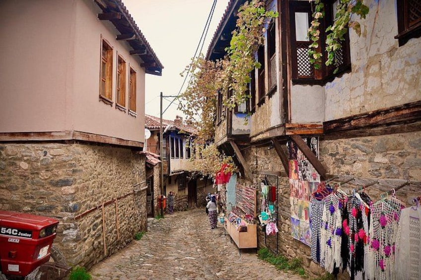 A narrow cobblestone street lined with traditional stone buildings, some with wooden shutters and hanging laundry. 3