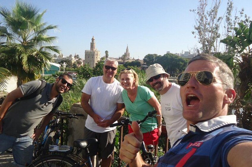 Un groupe de personnes à vélo, avec des palmiers et une tour historique en arrière-plan. 2