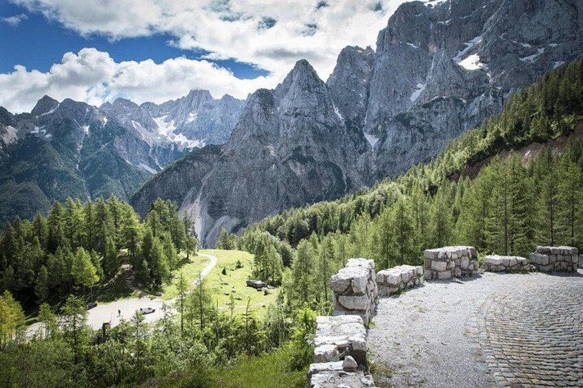Een bergachtig landschap met een kronkelend pad, dicht bos en rotsachtige uitstulpingen. 2