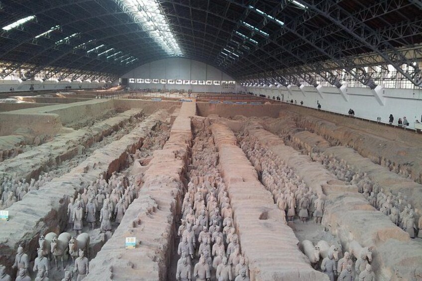 A large indoor archaeological site with rows of terracotta soldiers. 3