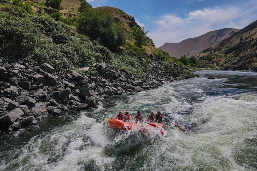 A group of people rafting on a river surrounded by rocky terrain and hills. 3