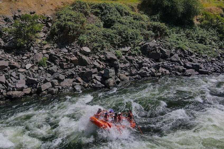 A group of people rafting down a river surrounded by rocks and greenery. 5