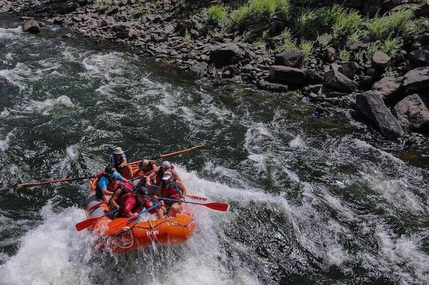 A group of people in a raft navigating a river with rapids. 4