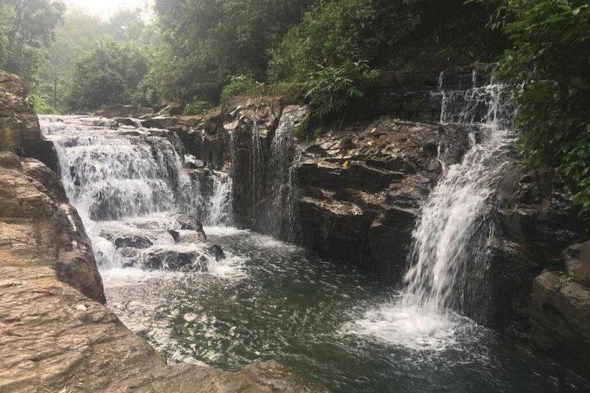 A waterfall cascading over rocks in a forested area. 3