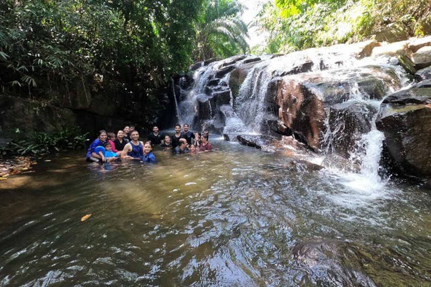 A group of people in a natural water setting with a waterfall. 4