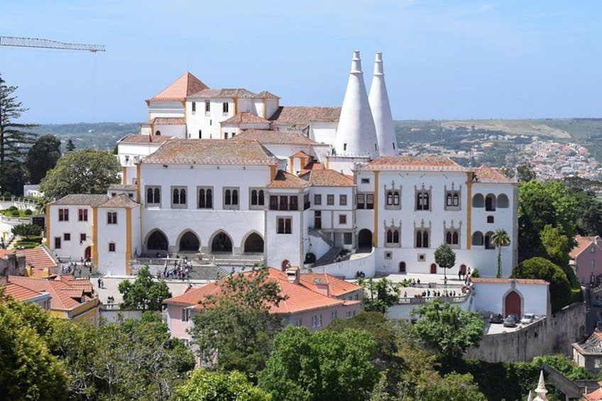 A historic white building with red-tiled roofs, two prominent white towers, and a surrounding urban landscape. 2