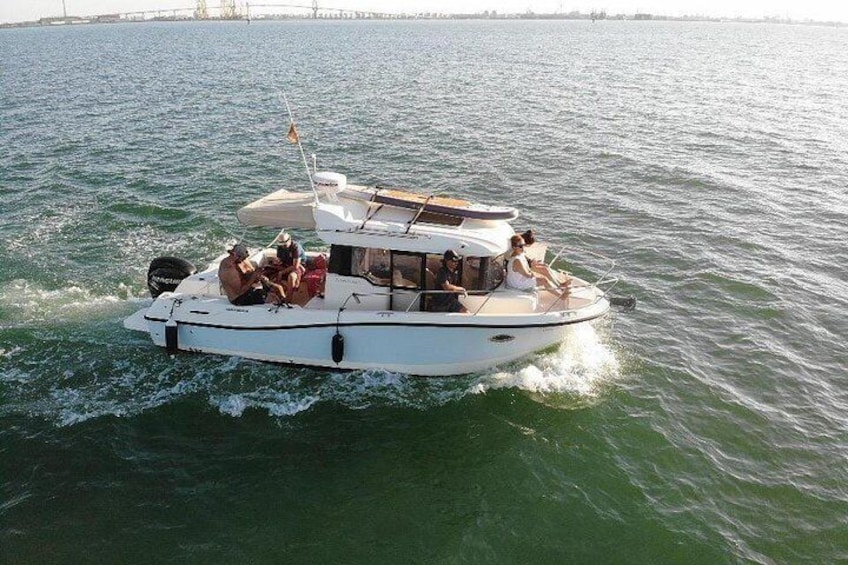 A white motorboat with a cabin and seating area, moving on a body of water. 1