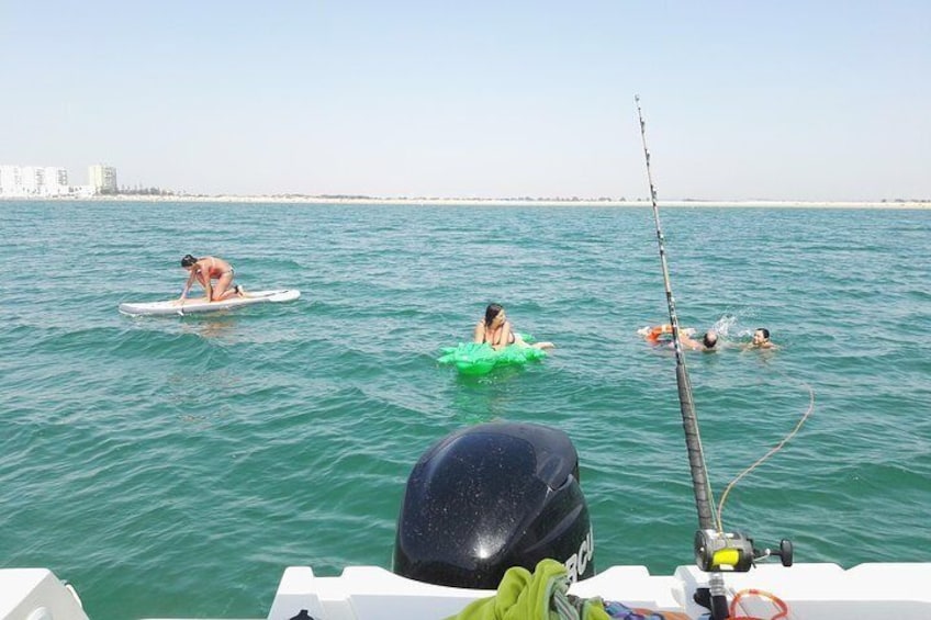 People swimming and surfing in the ocean, with a boat in the foreground. 1