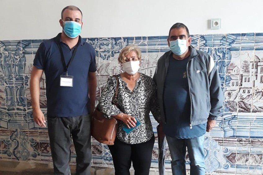 Tres personas frente a una pared con azulejos de diseño azul y blanco. 3