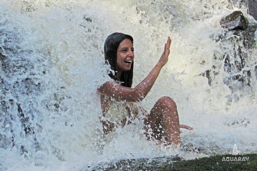 Una persona en un entorno acuático natural, posiblemente una cascada o río, con agua salpicando a su alrededor. 4