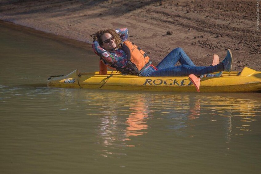 Una persona recostada en un kayak amarillo con la palabra 'ROCKER', flotando sobre aguas tranquilas. 2