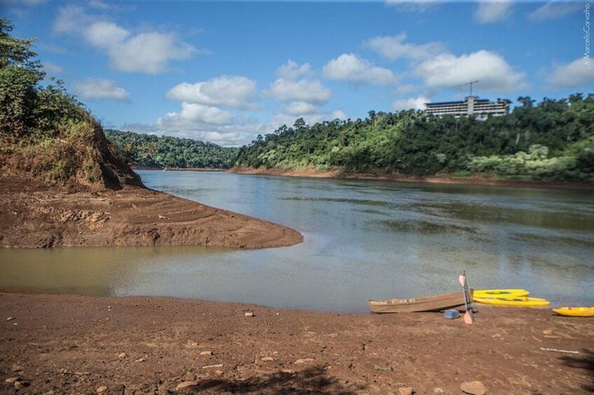 Orilla de río con kayaks y un edificio al fondo. 3