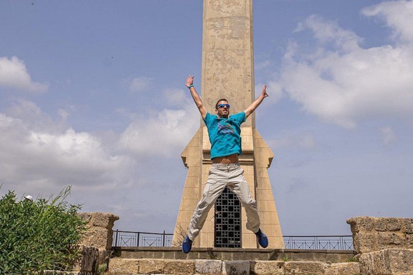 A person jumping in front of a tall monument with arms raised. 3