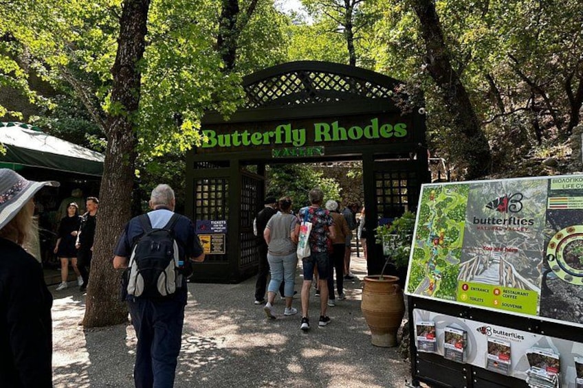 Een bordje van Butterfly Rhodes, met mensen die voorbijlopen. 3