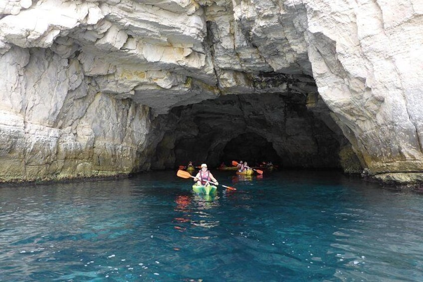 Un kayakista navegando por la entrada de una cueva rodeada de formaciones rocosas blancas. 3