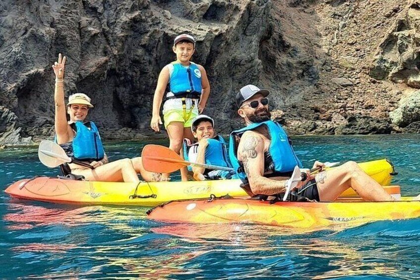 Un grupo de personas haciendo kayak en un cuerpo de agua con acantilados rocosos al fondo. 5