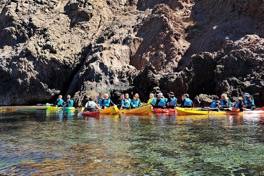 Un groupe de personnes pratiquant le kayak sur une rivière, avec des falaises rocheuses en arrière-plan. 2