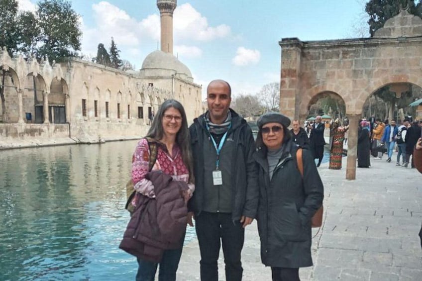 Three people standing by a body of water with historical architecture in the background. 3