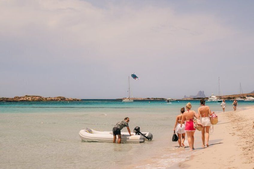 Ein Strand mit Menschen, einem Boot und Segelbooten in der Ferne. 4