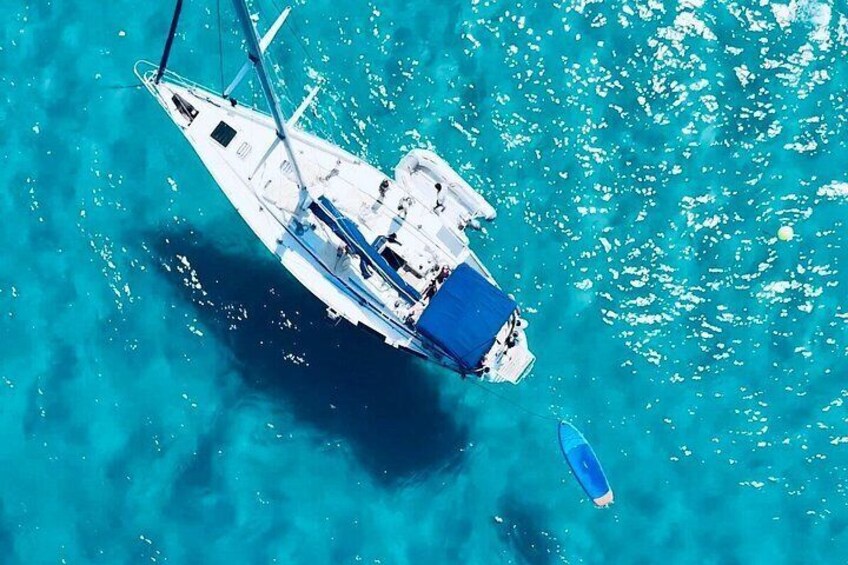 Un voilier sur une eau turquoise, avec une voile bleue. 1