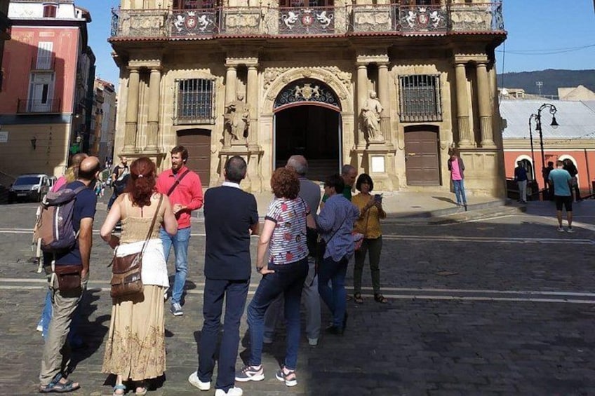 Een groep mensen staat voor een historisch gebouw met versierde architectuur. 2