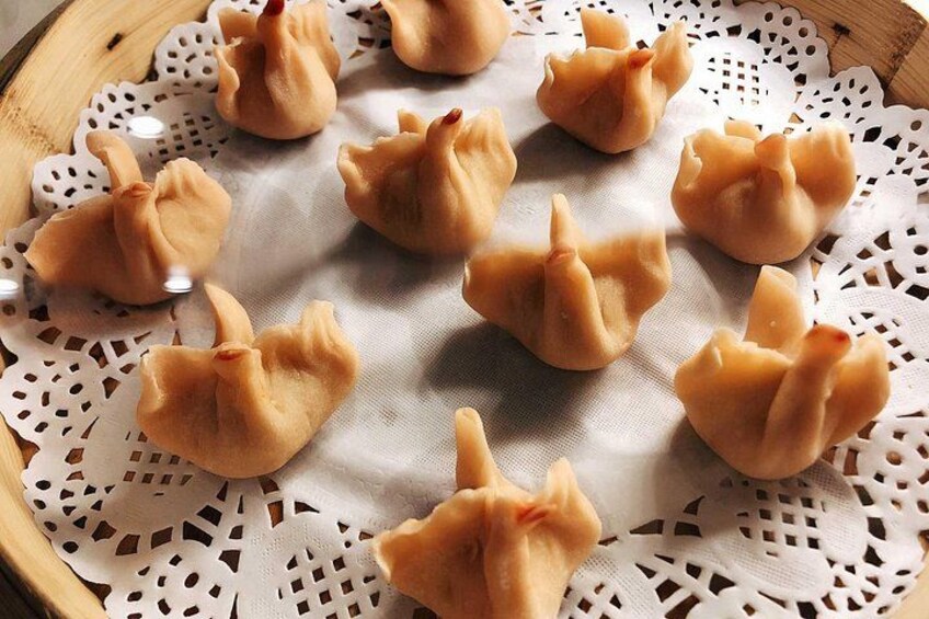 A tray of dumplings on a white doily. 4