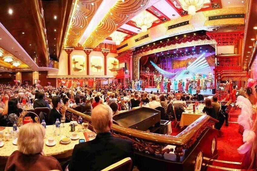 A crowded theater with ornate decorations and a stage performance. 1