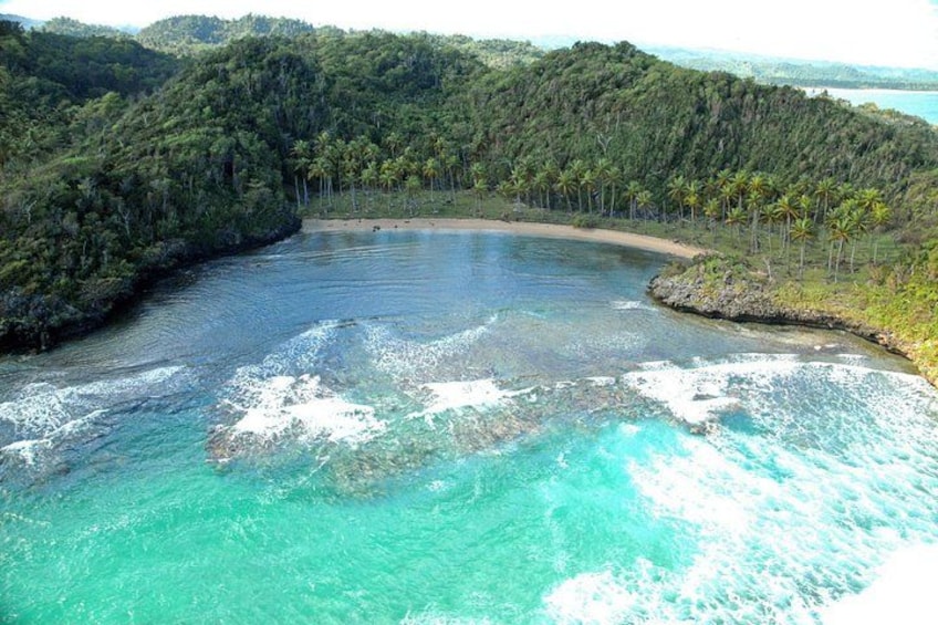 Paisaje costero con aguas turquesas cristalinas, una playa de arena y densa vegetación tropical. 5