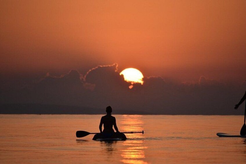 En person sidder på et paddleboard i solnedgangen. 1