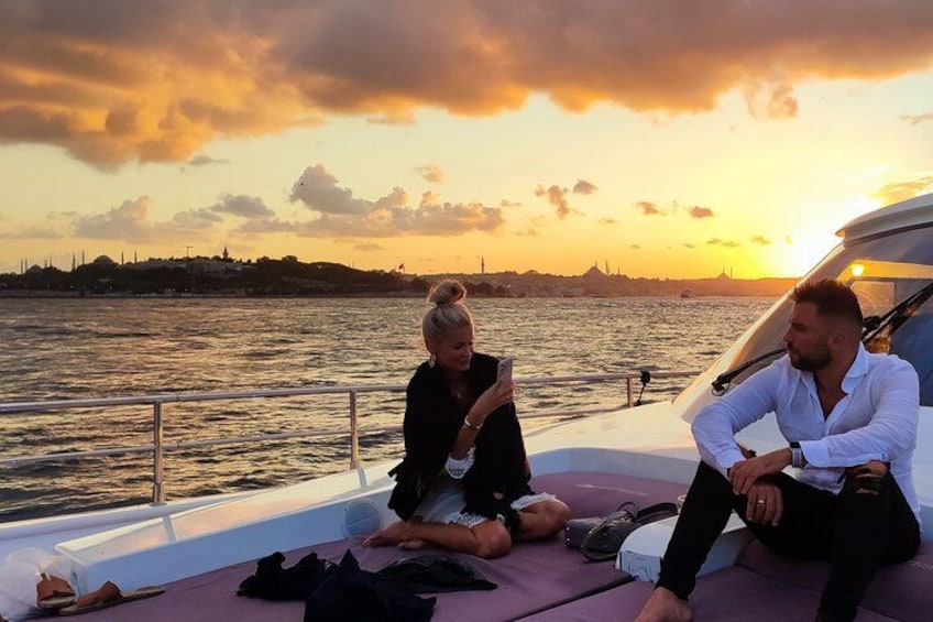 Two people sitting on a boat with a sunset in the background. 3