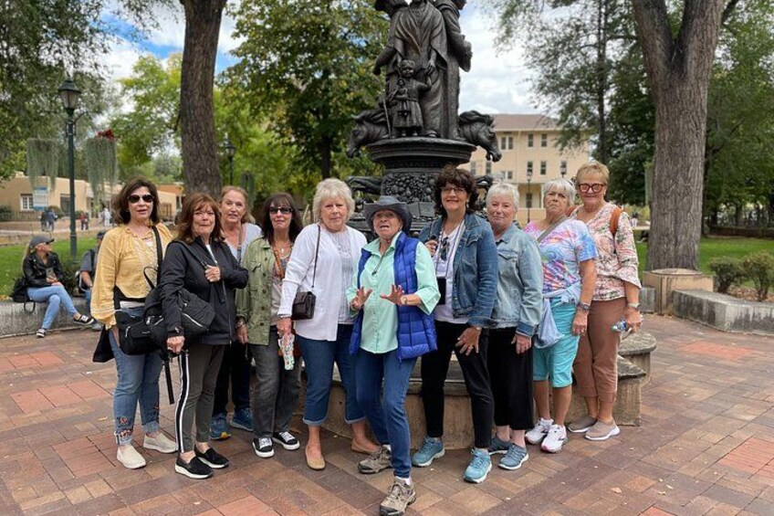 Un grupo de personas posando frente a una estatua en un parque. 3